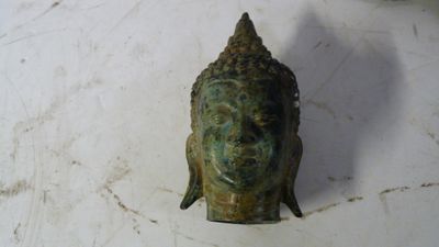 une petite statue représentant une tête de Bouddha posée sur une table