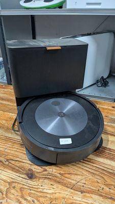 the robot is sitting on the wooden floor next to the tv