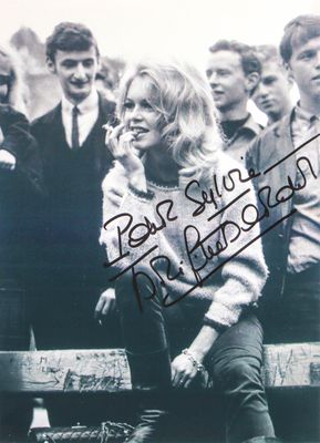 an old photo of a woman sitting on a bench in front of a group of young men