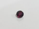 a close up of a red garnet stone on a white surface