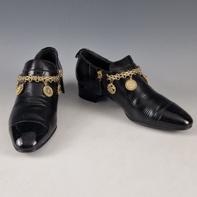 une paire de chaussures en cuir noir ornées de chaînes dorées