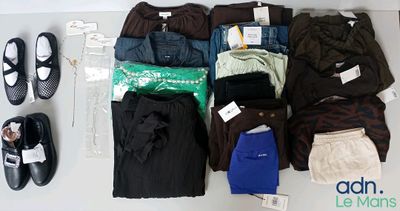Plusieurs paires de pantalons et de chaussures sont disposées sur une table