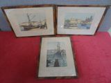 trois photos encadrées représentant des navires, exposées sur une table rouge