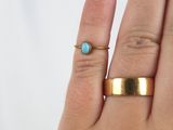 a woman ' s hand with a gold ring and a turquoise stone
