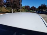 a white car parked in a parking lot with trees in the background