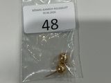 un sachet de perles dorées posé sur une table blanche