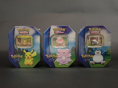 Trois figurines de Pokémon sont alignées sur une table