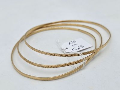 a close up of a gold bang bracelet with a tag on it