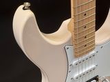 a close up of a white electric guitar on a black background