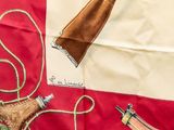 a red and white flag with a picture of a gun and a knife