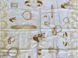 une image représentant une écharpe blanche ornée de bijoux dorés