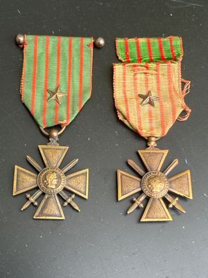 two medals and a cross on a table with a red and green ribbon