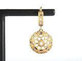 a close up of a gold pendant on a black stand