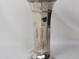 a silver vase that is sitting on a white surface