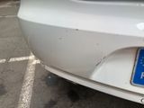a white car with a blue license plate in a parking lot