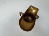 a small bronze object on a white surface