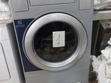 une machine à laver et un sèche-linge dans une pièce où il y a beaucoup de vêtements par terre