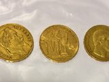 three gold sovereigns in plastic bags on a white surface