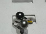 a ring with two black pearls on it in a display case