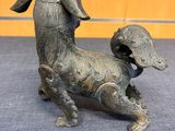 bronze statue of a dog with a bell on its head