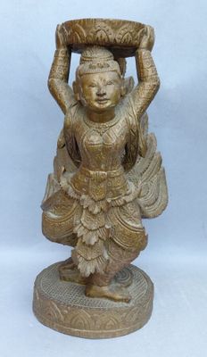 une statue représentant une femme tenant un panier sur la tête