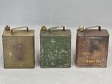 three old tin cans are lined up on a white surface