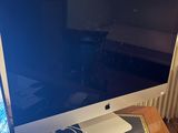 un écran d'ordinateur Apple posé sur un bureau, à côté d'une souris