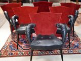 Plusieurs fauteuils en cuir noir sont disposés en cercle sur un tapis rouge