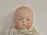a baby doll that is sitting on a white surface