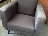 a grey chair that is sitting in front of a wooden wall