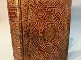 un vieux livre avec une couverture dorée et rouge sur fond blanc