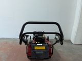 a red and black lawn mower sitting in a room