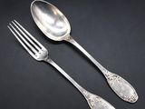 two silver spoons and a fork on a black surface