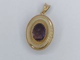a close up of a gold locke with a purple stone in the center