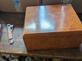 une petite boîte en bois contenant un couteau et un repose-couteau, posée sur une table