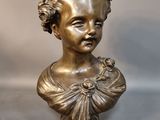 bronze bust of a young girl with a flower in her hair