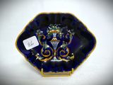 an image of a blue and gold plate with a vase on it