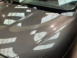 a black car parked in a showroom with a clock on the hood