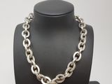 un gros plan sur un collier à chaîne en argent porté par un mannequin