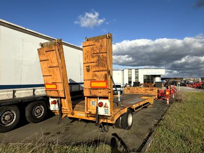 un camion garé dans l'herbe, avec une remorque derrière lui