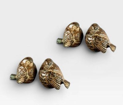 three bronze birds sitting on top of each other on a white surface