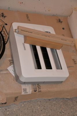 a white toaster sitting on top of a cardboard box next to a frying pan