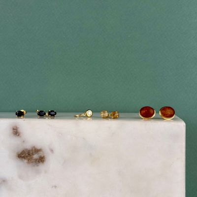 cinq paires de boucles d'oreilles posées sur un bloc de marbre