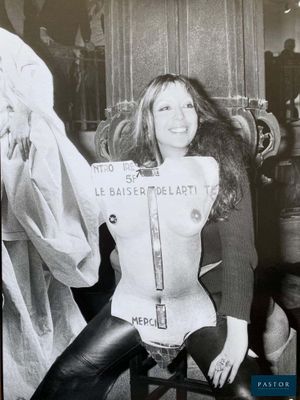 photo en noir et blanc d'une femme assise sur une chaise, tenant une pancarte