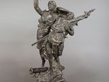 a silver statue of a woman holding a bird on top of a wooden base