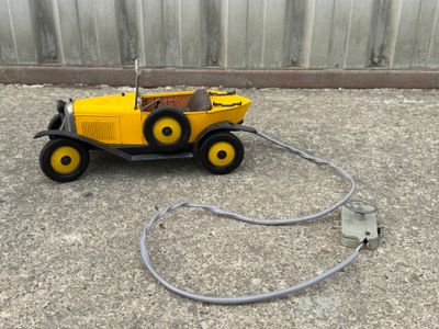un petit camion jaune auquel est fixé un tuyau