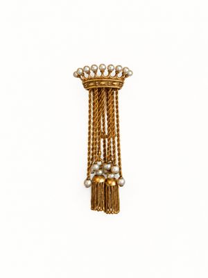 une image représentant une broche en or ornée de perles et de pompons