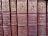 several old books are lined up on a shelf in a library