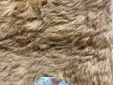 a brown fur bag with a metal handle on a table