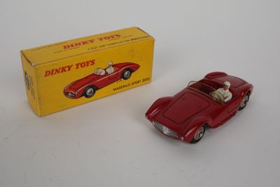 an old red toy car sitting next to a boxed box